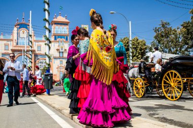 Seville, İspanya - 1 Mayıs 2022 Sevillianlar geleneksel Endülüs tarzında giyinmiş bir at arabasıyla İspanya 'nın en ünlü festivali olan Feria de Sevilla' nın koridorlarında dolaşıyorlar.