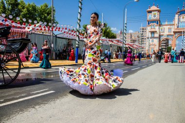 Seville, İspanya - 1 Mayıs 2022 Sevillianlar geleneksel Endülüs tarzında giyinmiş bir at arabasıyla İspanya 'nın en ünlü festivali olan Feria de Sevilla' nın koridorlarında dolaşıyorlar.