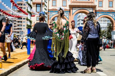 Seville, İspanya - 1 Mayıs 2022 Sevilla 'lılar geleneksel Endülüs tarzında giyinmiş Feria de Seville koridorlarında dolaşıyorlar.