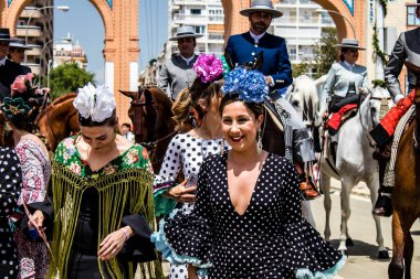 Seville, İspanya - 1 Mayıs 2022 Sevilla 'lılar geleneksel Endülüs tarzında giyinmiş Feria de Seville koridorlarında dolaşıyorlar.