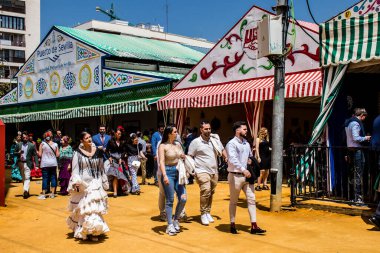 Seville, İspanya - 1 Mayıs 2022 Sevilla 'lılar geleneksel Endülüs tarzında giyinmiş Feria de Seville koridorlarında dolaşıyorlar.