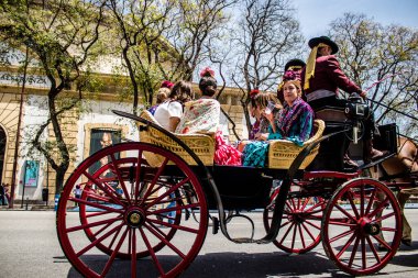 Seville, İspanya... 1 Mayıs 2022 Sevilla 'lılar geleneksel Endülüs tarzında giyinip Seville sokaklarında at arabasıyla geziyorlar.