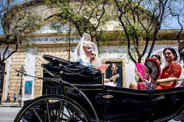 Seville, İspanya... 1 Mayıs 2022 Sevilla 'lılar geleneksel Endülüs tarzında giyinip Seville sokaklarında at arabasıyla geziyorlar.