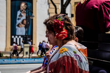 Seville, İspanya... 1 Mayıs 2022 Sevilla 'lılar geleneksel Endülüs tarzında giyinip Seville sokaklarında at arabasıyla geziyorlar.