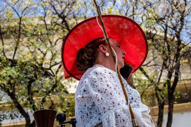 Seville, İspanya... 1 Mayıs 2022 Sevilla 'lılar geleneksel Endülüs tarzında giyinip Seville sokaklarında at arabasıyla geziyorlar.