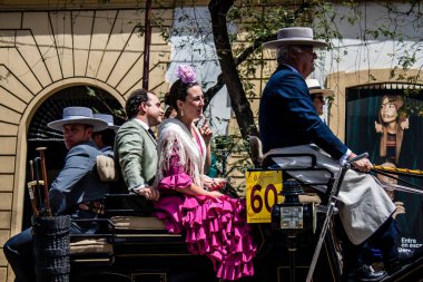 Seville, İspanya... 1 Mayıs 2022 Sevilla 'lılar geleneksel Endülüs tarzında giyinip Seville sokaklarında at arabasıyla geziyorlar.