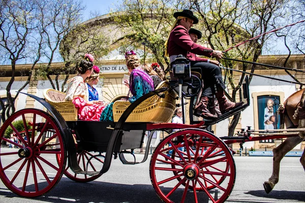 Seville, İspanya... 1 Mayıs 2022 Sevilla 'lılar geleneksel Endülüs tarzında giyinip Seville sokaklarında at arabasıyla geziyorlar.