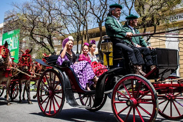 Seville, İspanya... 1 Mayıs 2022 Sevilla 'lılar geleneksel Endülüs tarzında giyinip Seville sokaklarında at arabasıyla geziyorlar.