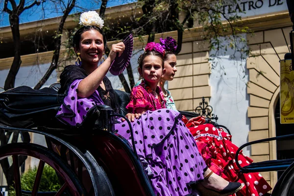 Seville, İspanya... 1 Mayıs 2022 Sevilla 'lılar geleneksel Endülüs tarzında giyinip Seville sokaklarında at arabasıyla geziyorlar.