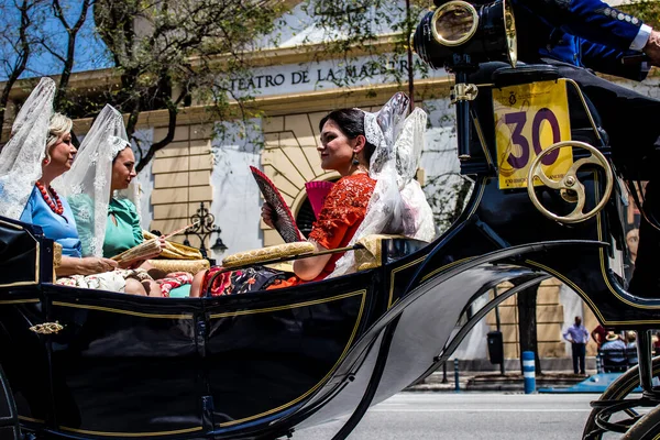 Seville, İspanya... 1 Mayıs 2022 Sevilla 'lılar geleneksel Endülüs tarzında giyinip Seville sokaklarında at arabasıyla geziyorlar.