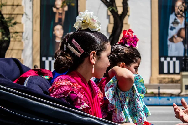 Seville, İspanya... 1 Mayıs 2022 Sevilla 'lılar geleneksel Endülüs tarzında giyinip Seville sokaklarında at arabasıyla geziyorlar.