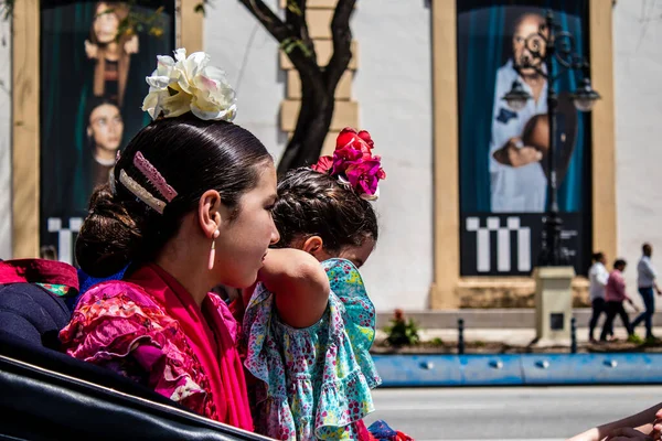 Seville, İspanya... 1 Mayıs 2022 Sevilla 'lılar geleneksel Endülüs tarzında giyinip Seville sokaklarında at arabasıyla geziyorlar.