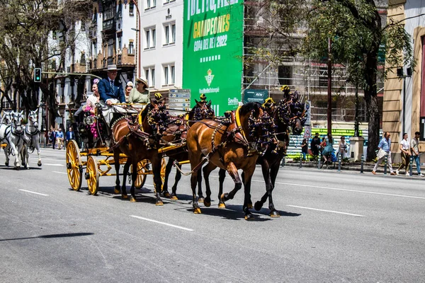 Seville, İspanya... 1 Mayıs 2022 Sevilla 'lılar geleneksel Endülüs tarzında giyinip Seville sokaklarında at arabasıyla geziyorlar.