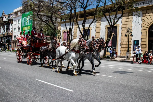 Seville, İspanya... 1 Mayıs 2022 Sevilla 'lılar geleneksel Endülüs tarzında giyinip Seville sokaklarında at arabasıyla geziyorlar.