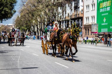 Seville, İspanya... 1 Mayıs 2022 Sevilla 'lılar geleneksel Endülüs tarzında giyinip Seville sokaklarında at arabasıyla geziyorlar.
