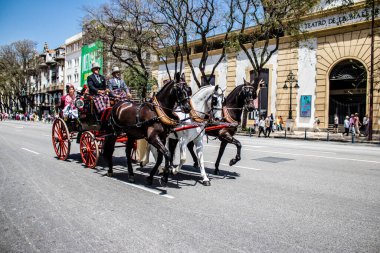 Seville, Spain- May 01, 2022 Sevillians dressed in traditional Andalusian way riding in a carriage with horses through the streets of Seville, celebration  back after two years of absence due to covid