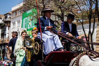 Seville, İspanya... 1 Mayıs 2022 Sevilla 'lılar geleneksel Endülüs tarzında giyinip Seville sokaklarında at arabasıyla geziyorlar.