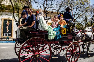 Seville, İspanya... 1 Mayıs 2022 Sevilla 'lılar geleneksel Endülüs tarzında giyinip Seville sokaklarında at arabasıyla geziyorlar.