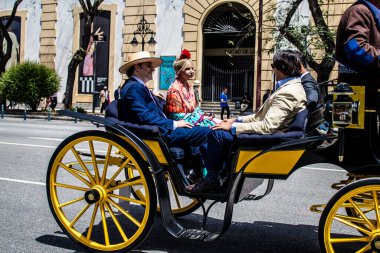 Seville, İspanya... 1 Mayıs 2022 Sevilla 'lılar geleneksel Endülüs tarzında giyinip Seville sokaklarında at arabasıyla geziyorlar.
