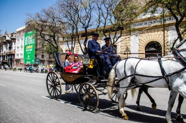 Seville, Spain- May 01, 2022 Sevillians dressed in traditional Andalusian way riding in a carriage with horses through the streets of Seville, celebration  back after two years of absence due to covid