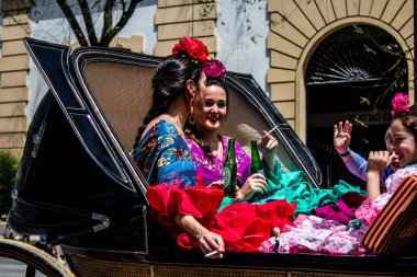 Seville, İspanya... 1 Mayıs 2022 Sevilla 'lılar geleneksel Endülüs tarzında giyinip Seville sokaklarında at arabasıyla geziyorlar.