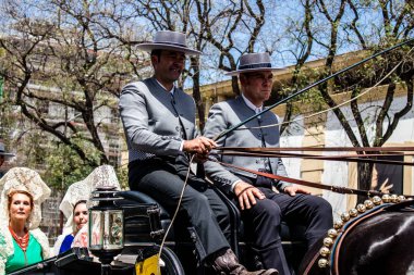 Seville, İspanya... 1 Mayıs 2022 Sevilla 'lılar geleneksel Endülüs tarzında giyinip Seville sokaklarında at arabasıyla geziyorlar.