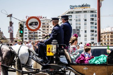 Seville, İspanya... 1 Mayıs 2022 Sevilla 'lılar geleneksel Endülüs tarzında giyinip Seville sokaklarında at arabasıyla geziyorlar.