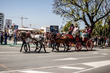 Seville, İspanya... 1 Mayıs 2022 Sevilla 'lılar geleneksel Endülüs tarzında giyinip Seville sokaklarında at arabasıyla geziyorlar.