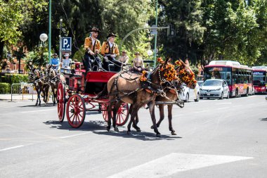 Seville, İspanya... 1 Mayıs 2022 Sevilla 'lılar geleneksel Endülüs tarzında giyinip Seville sokaklarında at arabasıyla geziyorlar.