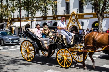 Seville, İspanya... 1 Mayıs 2022 Sevilla 'lılar geleneksel Endülüs tarzında giyinip Seville sokaklarında at arabasıyla geziyorlar.