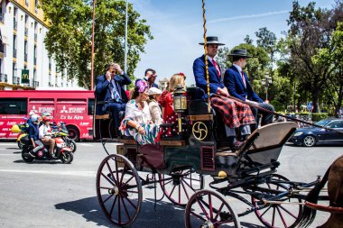 Seville, İspanya... 1 Mayıs 2022 Sevilla 'lılar geleneksel Endülüs tarzında giyinip Seville sokaklarında at arabasıyla geziyorlar.