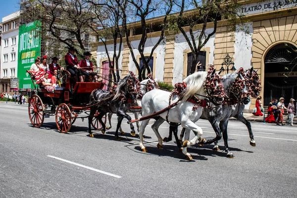 Seville, İspanya... 1 Mayıs 2022 Sevilla 'lılar geleneksel Endülüs tarzında giyinip Seville sokaklarında at arabasıyla geziyorlar.