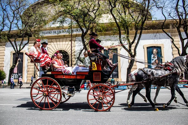 Seville, İspanya... 1 Mayıs 2022 Sevilla 'lılar geleneksel Endülüs tarzında giyinip Seville sokaklarında at arabasıyla geziyorlar.