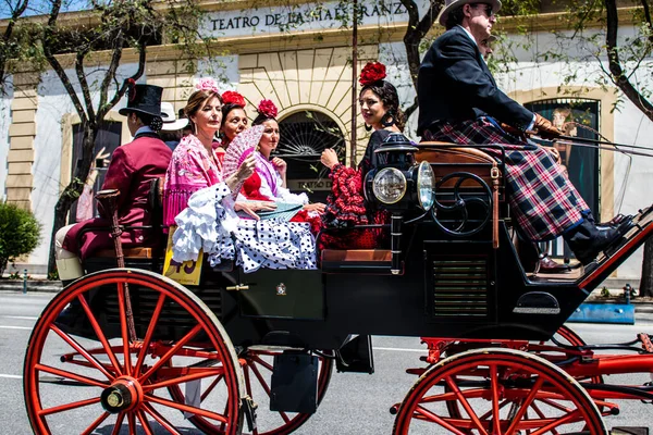 Seville, İspanya... 1 Mayıs 2022 Sevilla 'lılar geleneksel Endülüs tarzında giyinip Seville sokaklarında at arabasıyla geziyorlar.