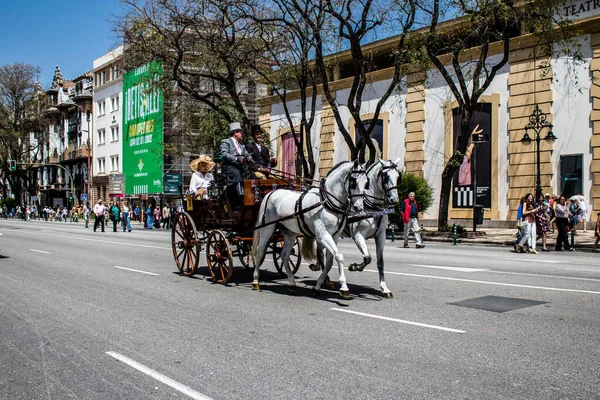 Seville, İspanya... 1 Mayıs 2022 Sevilla 'lılar geleneksel Endülüs tarzında giyinip Seville sokaklarında at arabasıyla geziyorlar.