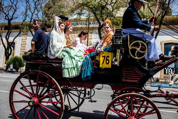 Seville, İspanya... 1 Mayıs 2022 Sevilla 'lılar geleneksel Endülüs tarzında giyinip Seville sokaklarında at arabasıyla geziyorlar.