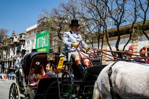 Seville, İspanya... 1 Mayıs 2022 Sevilla 'lılar geleneksel Endülüs tarzında giyinip Seville sokaklarında at arabasıyla geziyorlar.