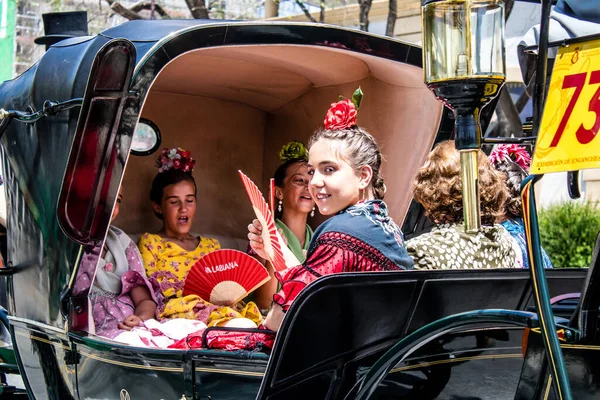 Seville, İspanya... 1 Mayıs 2022 Sevilla 'lılar geleneksel Endülüs tarzında giyinip Seville sokaklarında at arabasıyla geziyorlar.