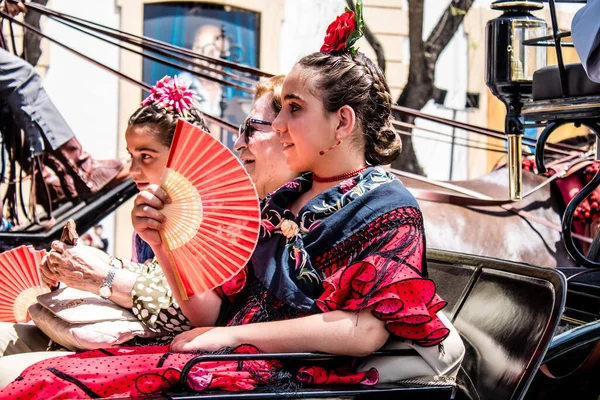 Seville, İspanya... 1 Mayıs 2022 Sevilla 'lılar geleneksel Endülüs tarzında giyinip Seville sokaklarında at arabasıyla geziyorlar.
