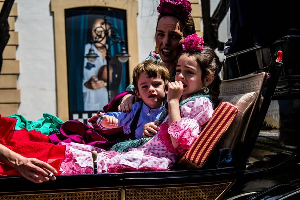 Seville, İspanya... 1 Mayıs 2022 Sevilla 'lılar geleneksel Endülüs tarzında giyinip Seville sokaklarında at arabasıyla geziyorlar.