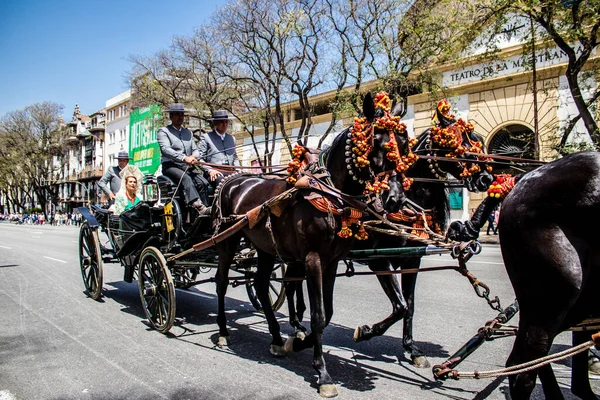 Seville, İspanya... 1 Mayıs 2022 Sevilla 'lılar geleneksel Endülüs tarzında giyinip Seville sokaklarında at arabasıyla geziyorlar.