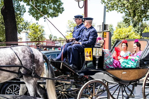 Seville, İspanya... 1 Mayıs 2022 Sevilla 'lılar geleneksel Endülüs tarzında giyinip Seville sokaklarında at arabasıyla geziyorlar.