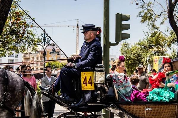 Seville, İspanya... 1 Mayıs 2022 Sevilla 'lılar geleneksel Endülüs tarzında giyinip Seville sokaklarında at arabasıyla geziyorlar.