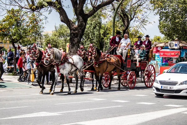 Seville, İspanya... 1 Mayıs 2022 Sevilla 'lılar geleneksel Endülüs tarzında giyinip Seville sokaklarında at arabasıyla geziyorlar.