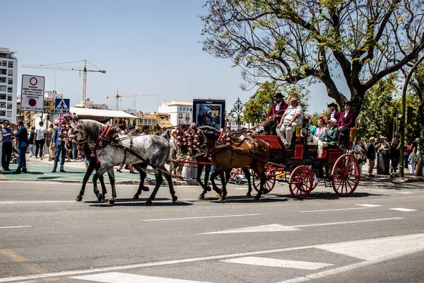 Seville, İspanya... 1 Mayıs 2022 Sevilla 'lılar geleneksel Endülüs tarzında giyinip Seville sokaklarında at arabasıyla geziyorlar.