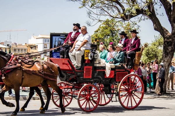 Seville, İspanya... 1 Mayıs 2022 Sevilla 'lılar geleneksel Endülüs tarzında giyinip Seville sokaklarında at arabasıyla geziyorlar.