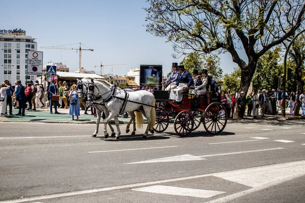 Seville, İspanya... 1 Mayıs 2022 Sevilla 'lılar geleneksel Endülüs tarzında giyinip Seville sokaklarında at arabasıyla geziyorlar.