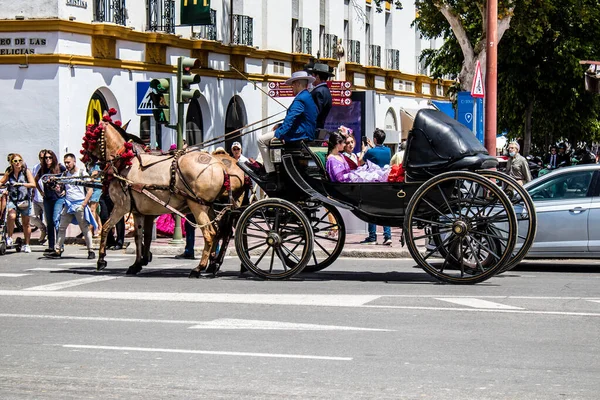Seville, İspanya... 1 Mayıs 2022 Sevilla 'lılar geleneksel Endülüs tarzında giyinip Seville sokaklarında at arabasıyla geziyorlar.