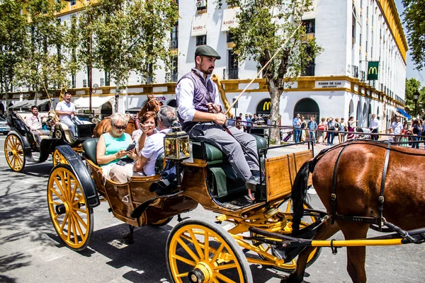 Seville, İspanya... 1 Mayıs 2022 Sevilla 'lılar geleneksel Endülüs tarzında giyinip Seville sokaklarında at arabasıyla geziyorlar.