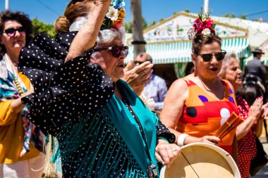 Seville, İspanya - 5 Mayıs 2022 Sevilla 'lılar geleneksel Endülüs tarzında giyinmiş Feria de Seville koridorlarında dolaşıyorlar.